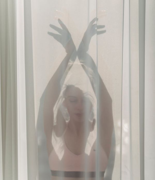 Woman in a peaceful yoga pose, bathed in soft, gentle light against a dark background.